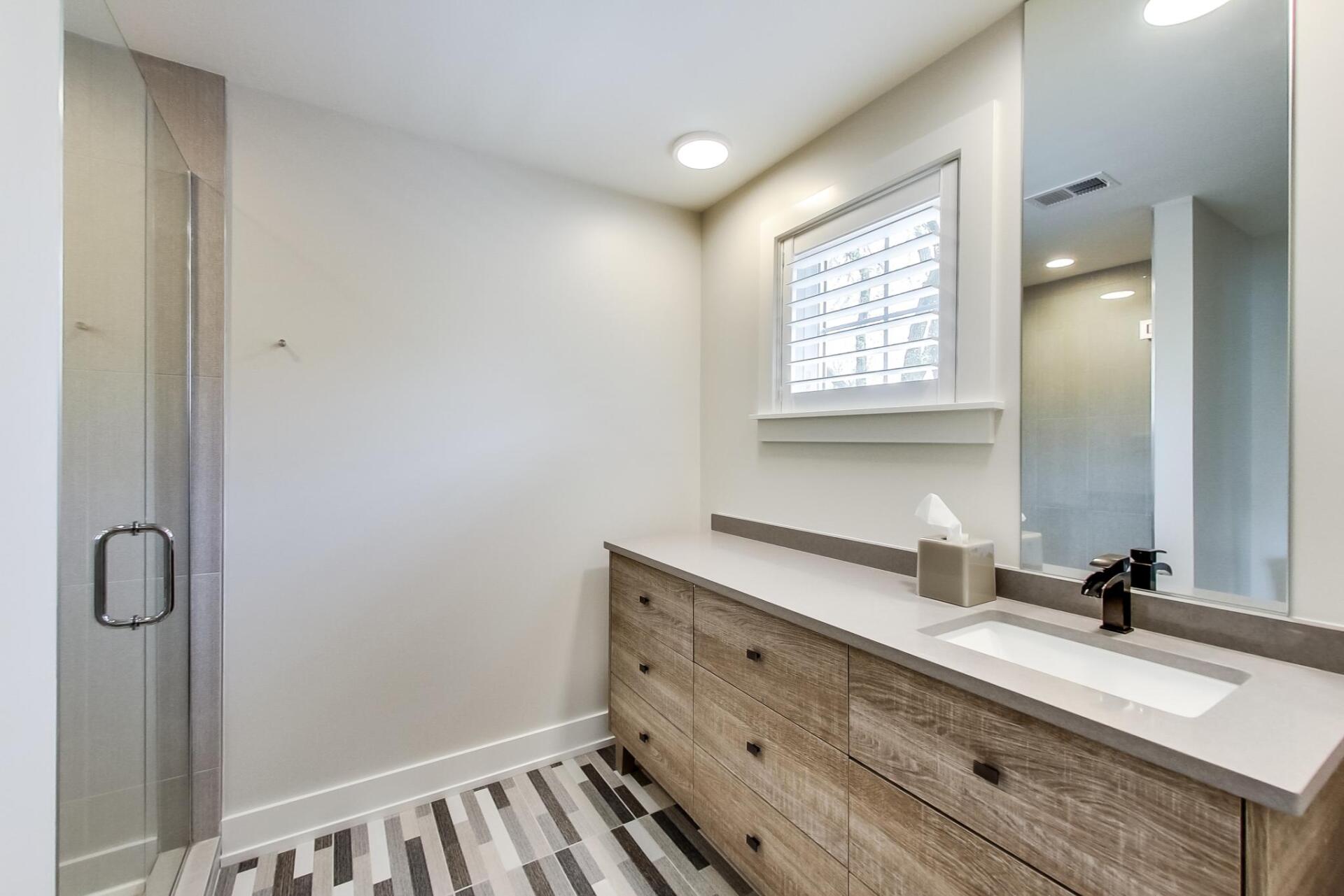 A bathroom with a sink , mirror and shower.