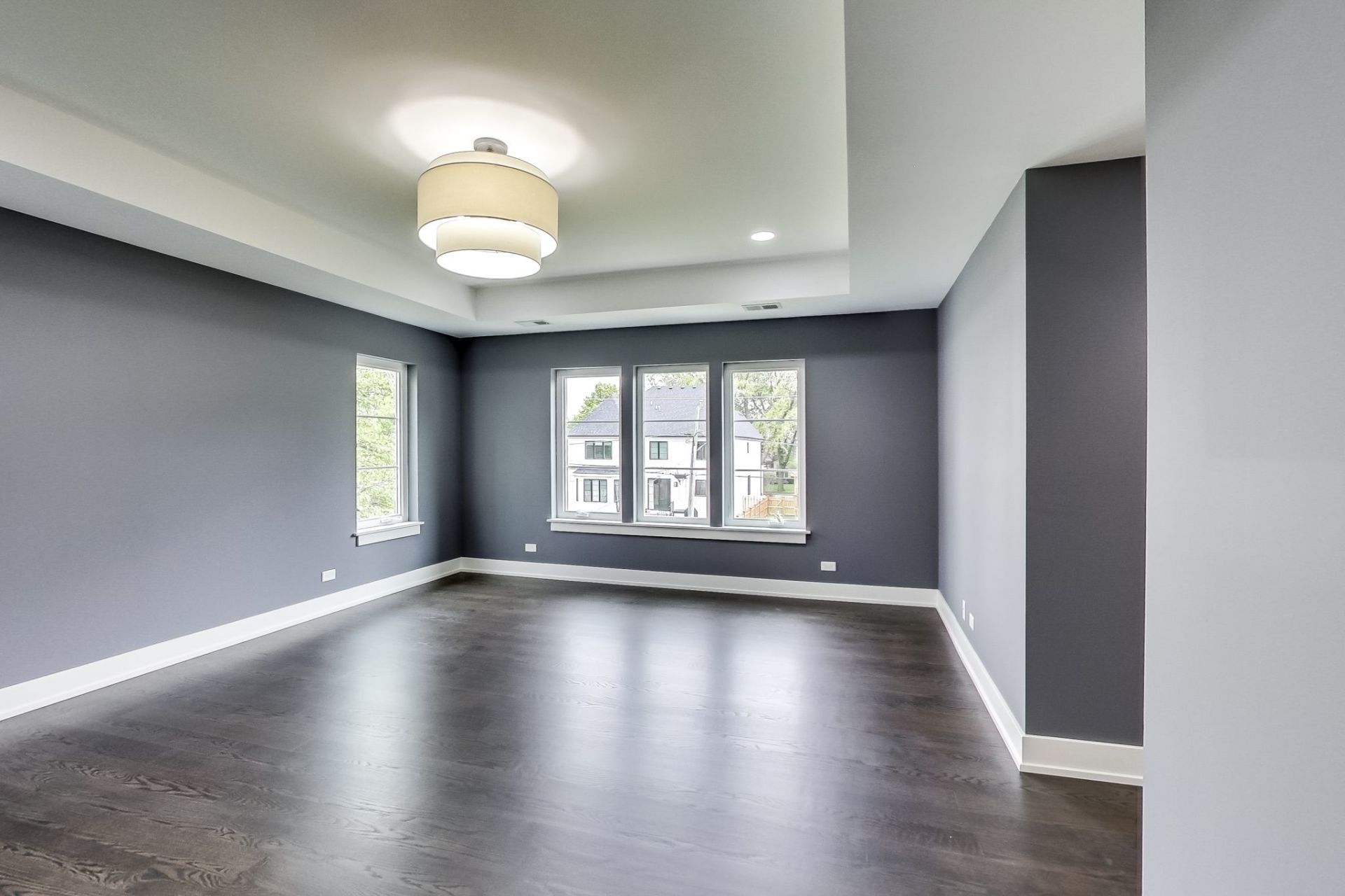 A large empty room with a lot of windows and a ceiling light.