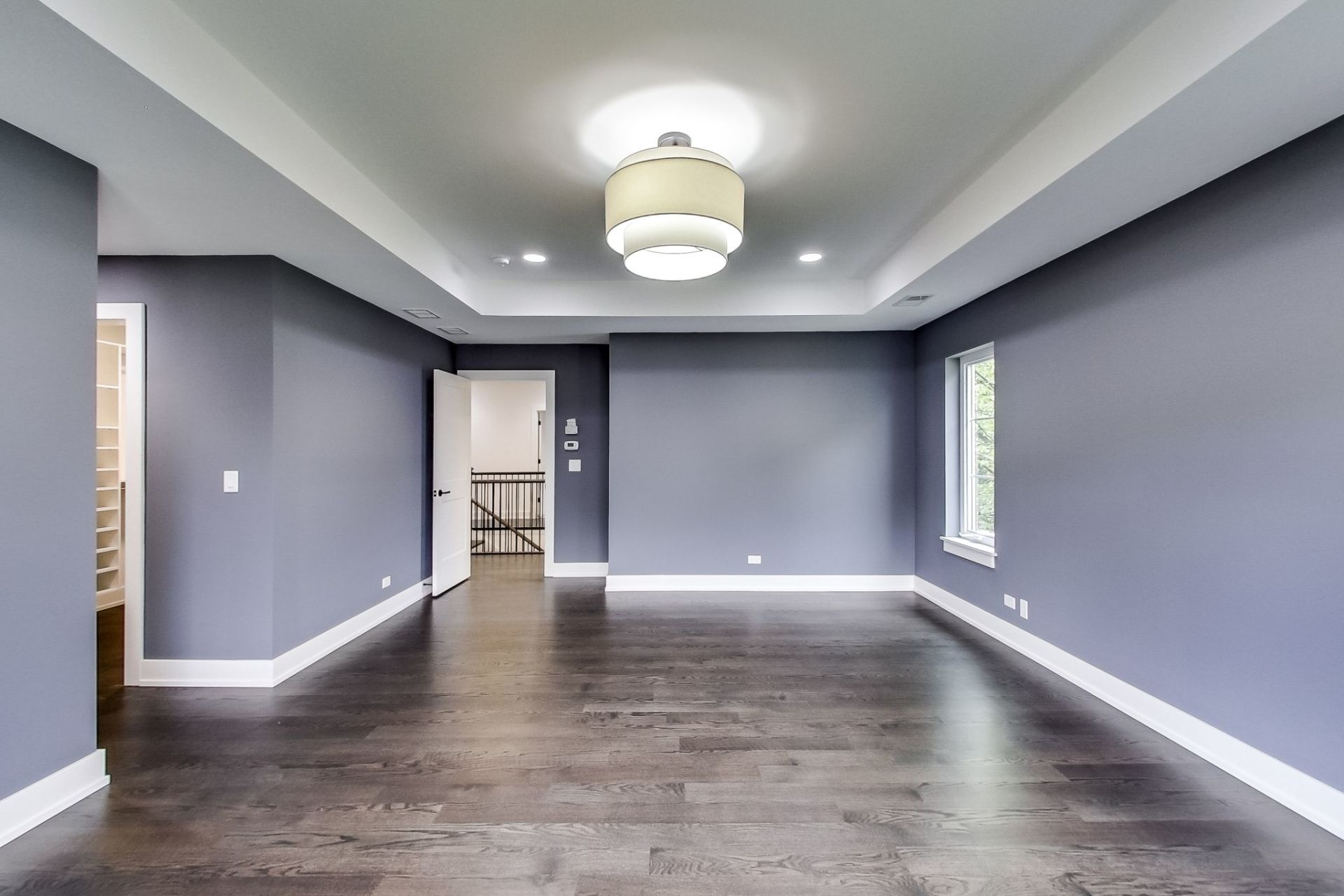A large empty room with gray walls and hardwood floors