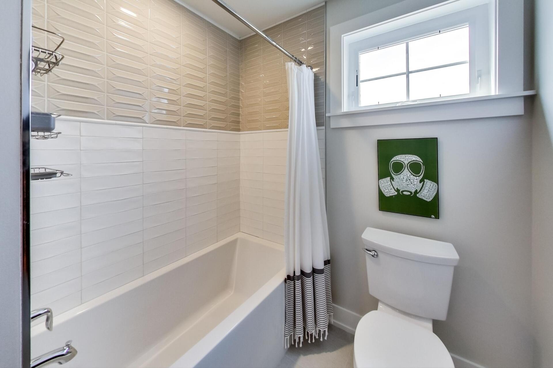 A bathroom with a toilet , tub , shower and window.