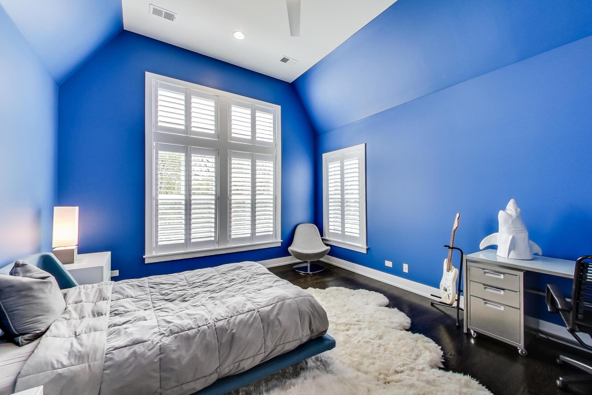A bedroom with blue walls and white shutters