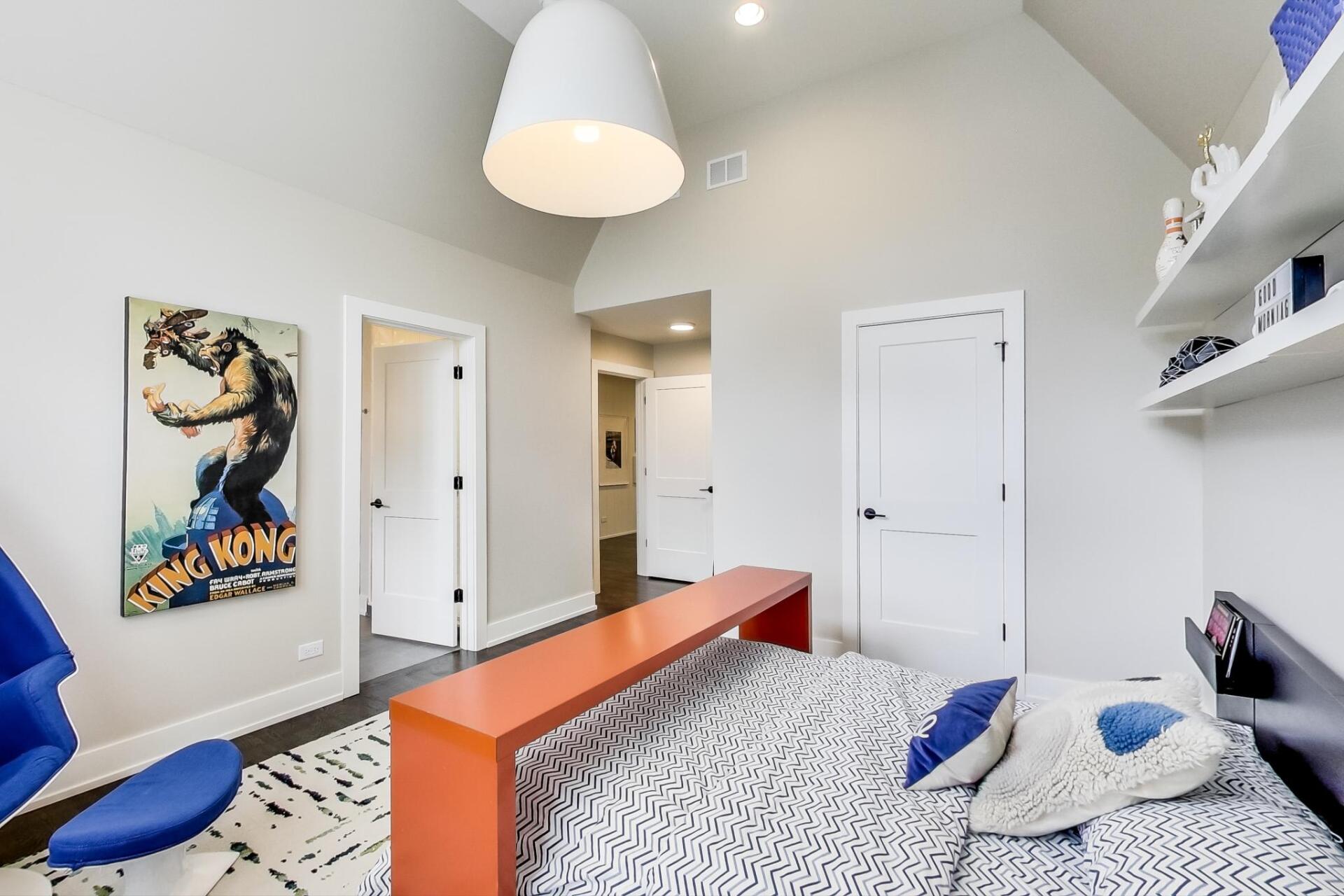 A bedroom with a bed , chair , table and a painting on the wall.