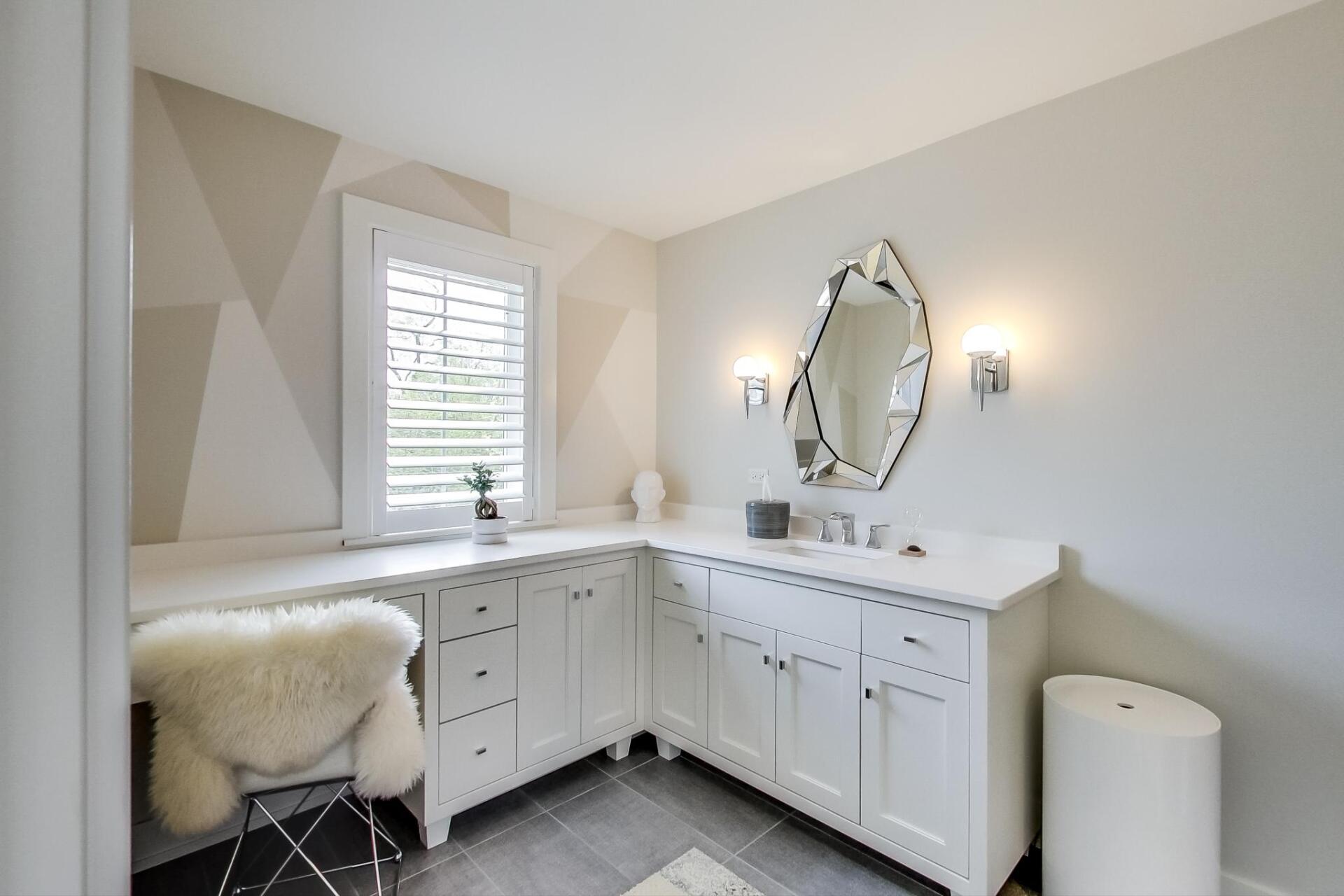 A bathroom with a sink , mirror and chair