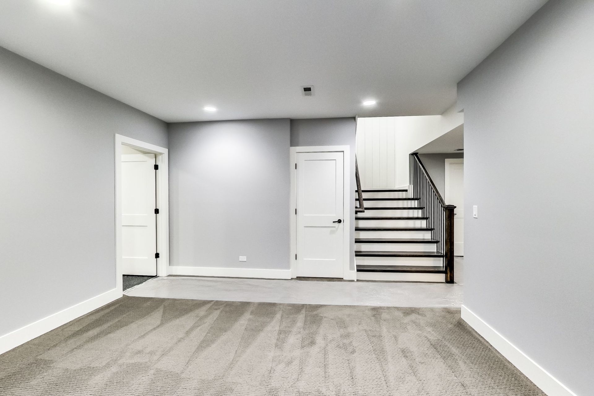 An empty basement with stairs leading up to the second floor.