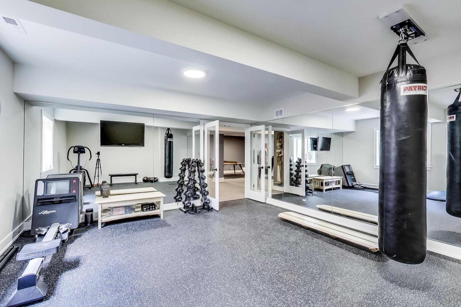 A basement gym with a boxing bag hanging from the ceiling.