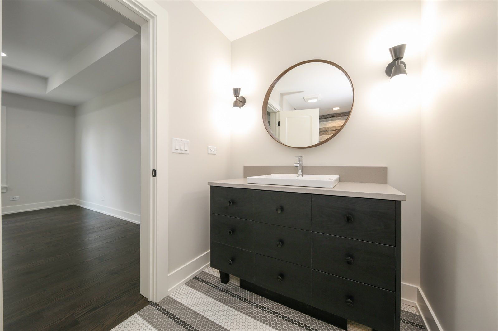 A bathroom with a sink , mirror and dresser.