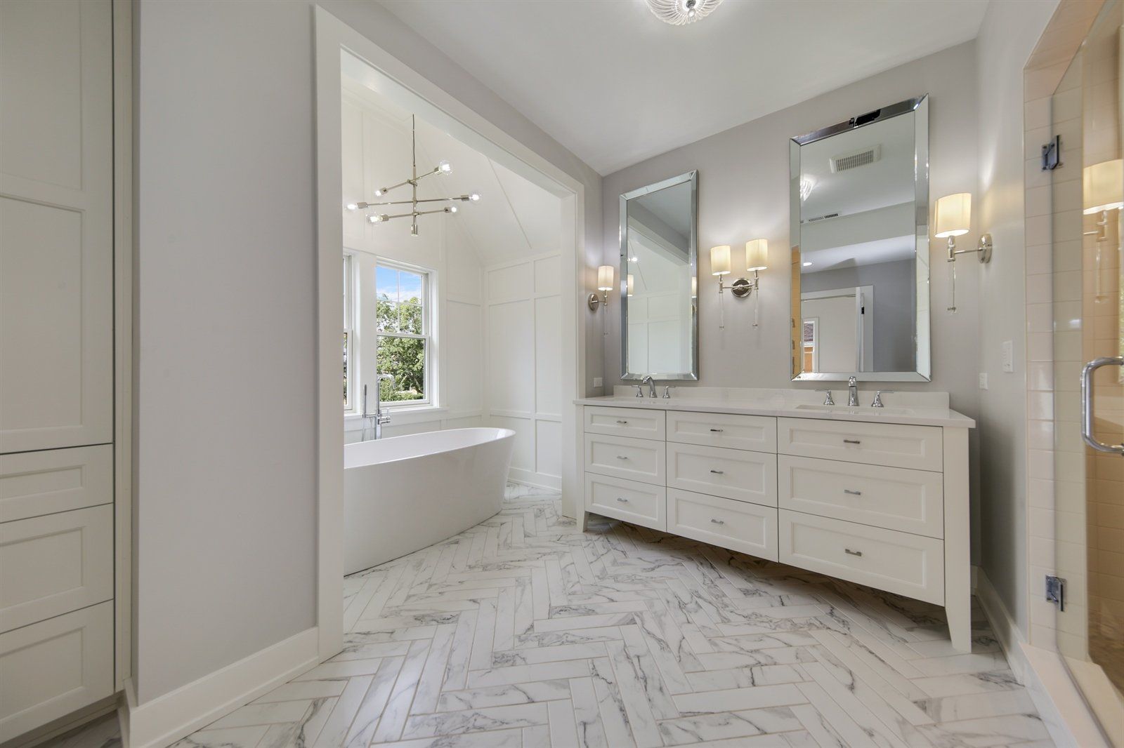 A bathroom with two sinks , two mirrors and a bathtub.