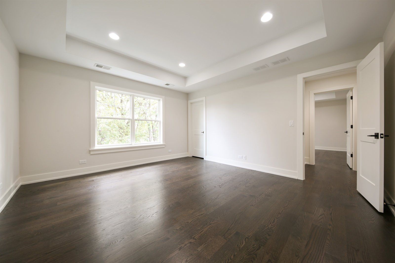 A large empty room with hardwood floors and white walls.