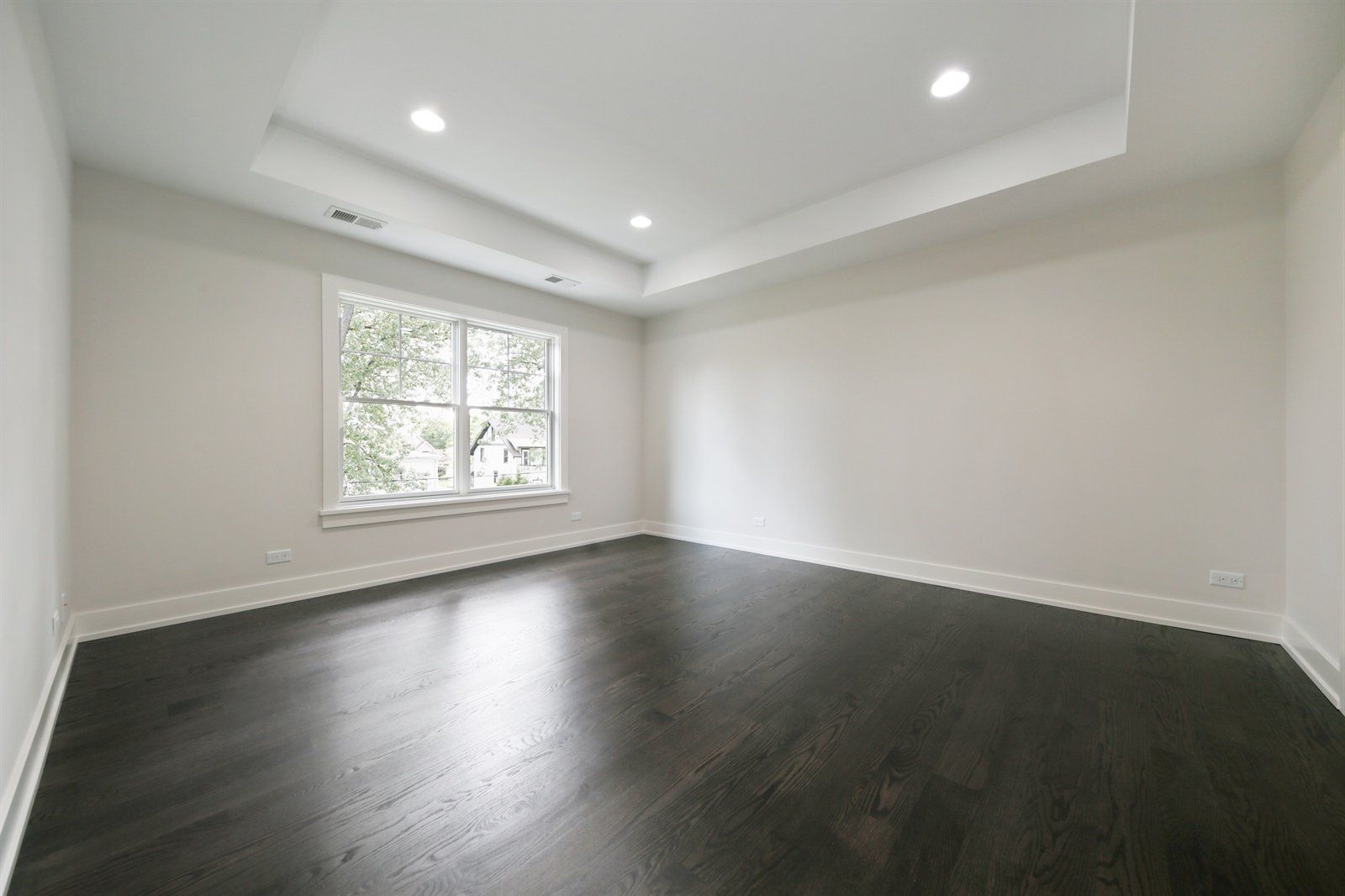 An empty room with hardwood floors and a window.