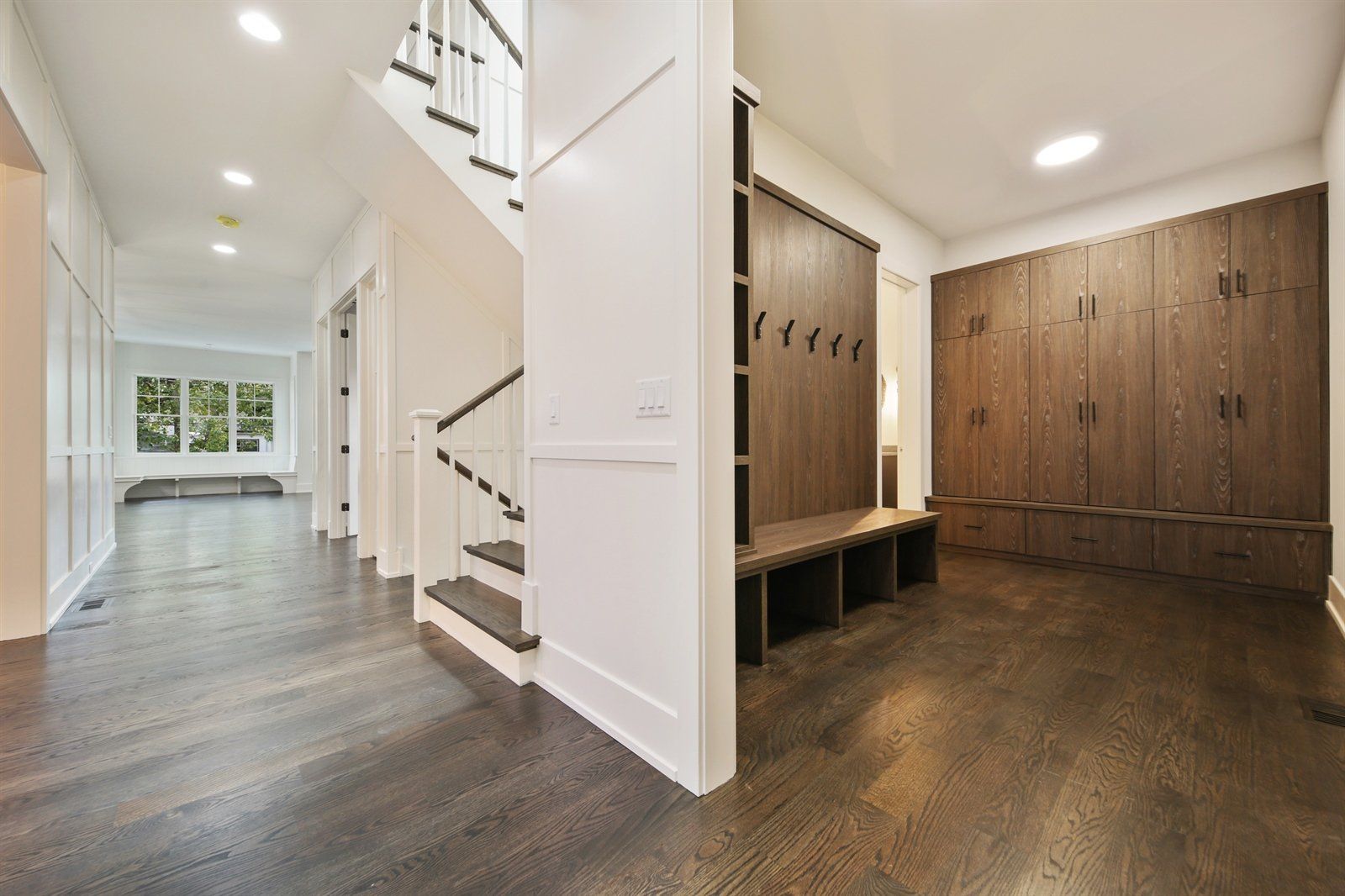 A hallway with wooden floors and stairs in a house