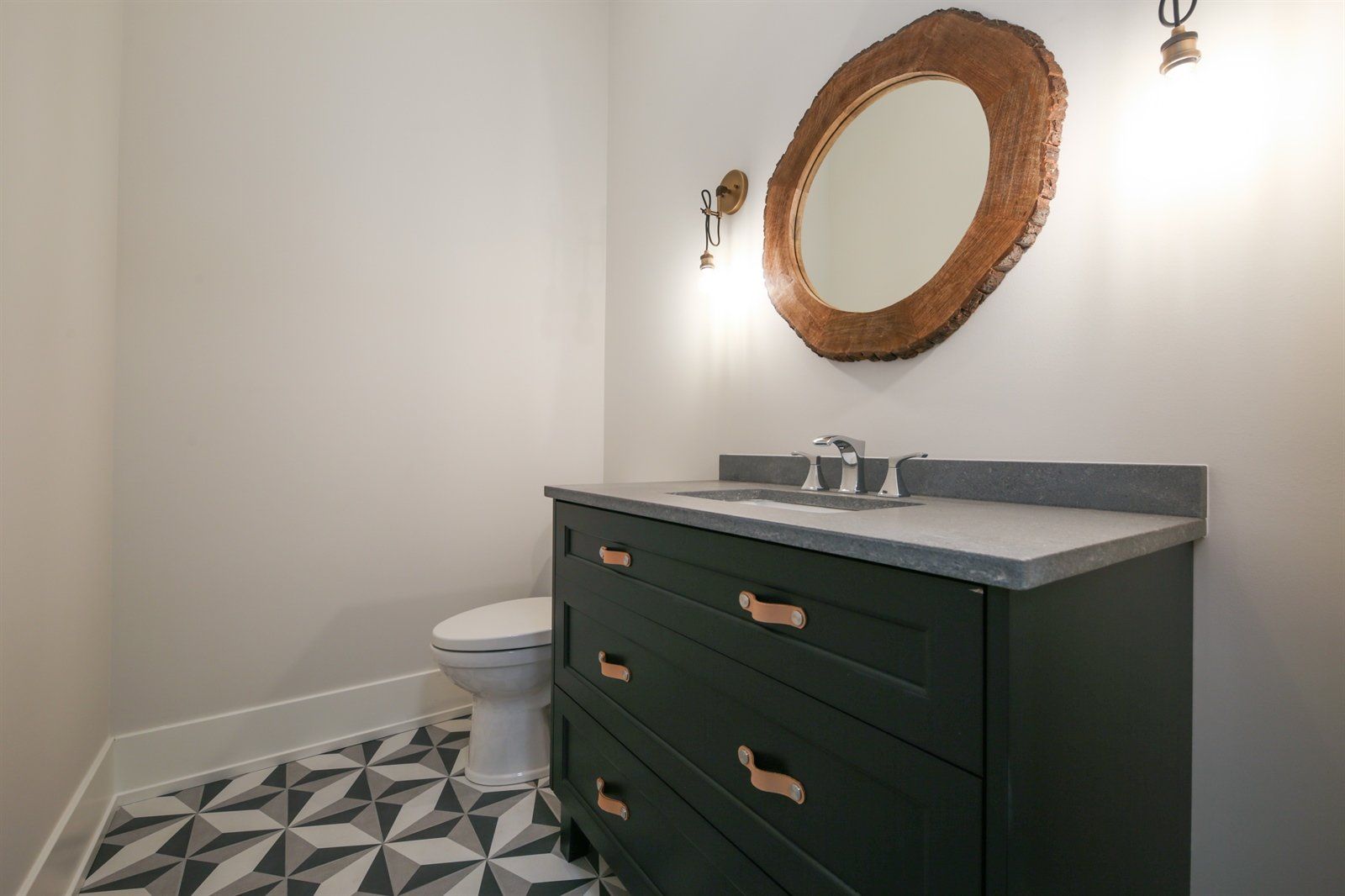 A bathroom with a toilet , sink , mirror and dresser.