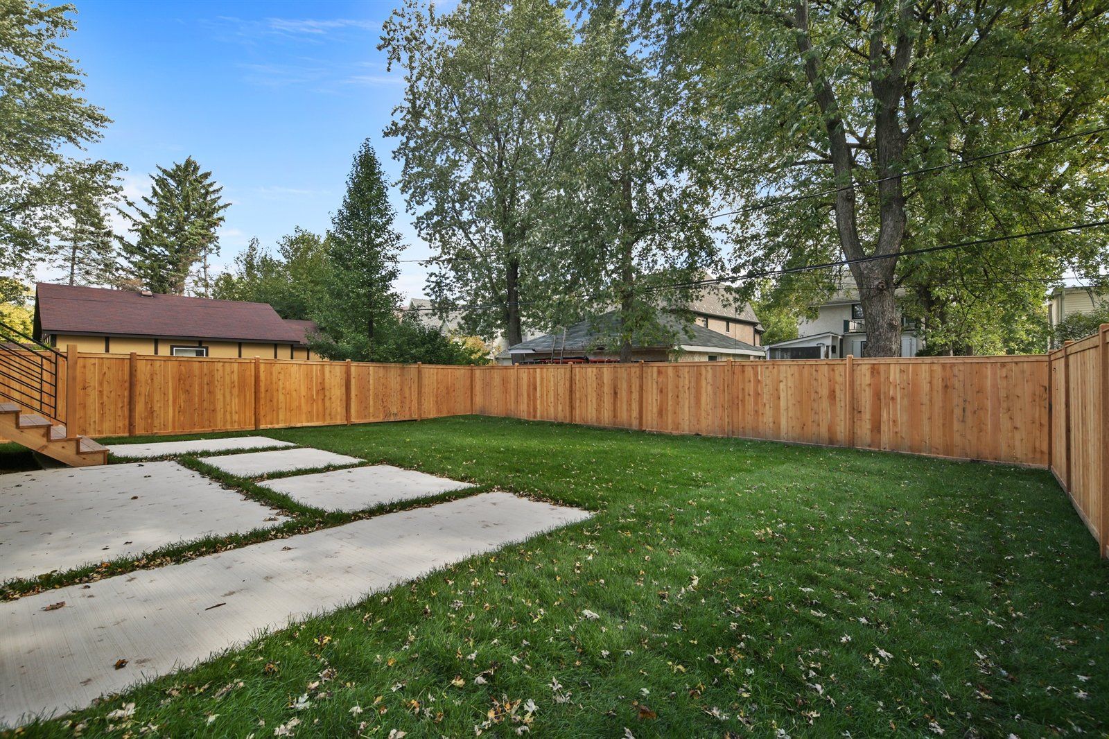 A backyard with a wooden fence and a concrete driveway.