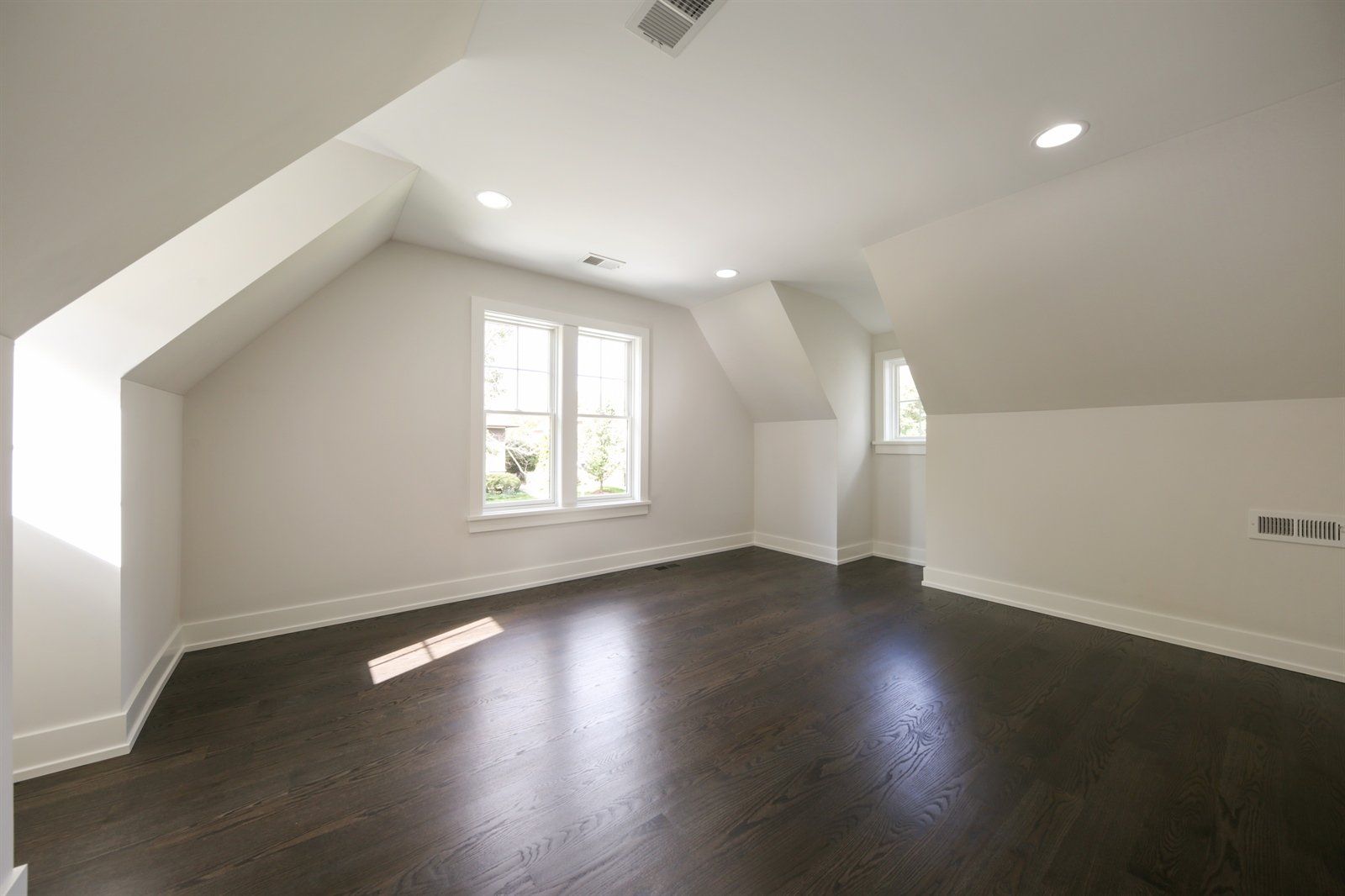 A large empty room with hardwood floors and white walls.