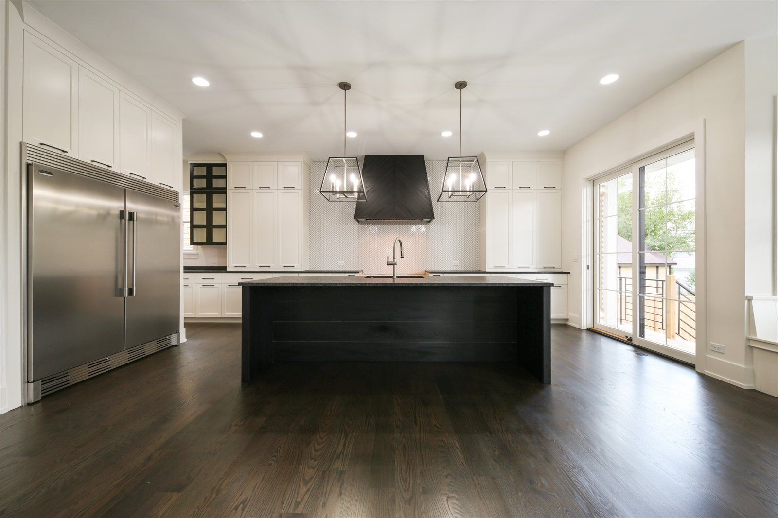 An empty kitchen with a large island and stainless steel appliances.