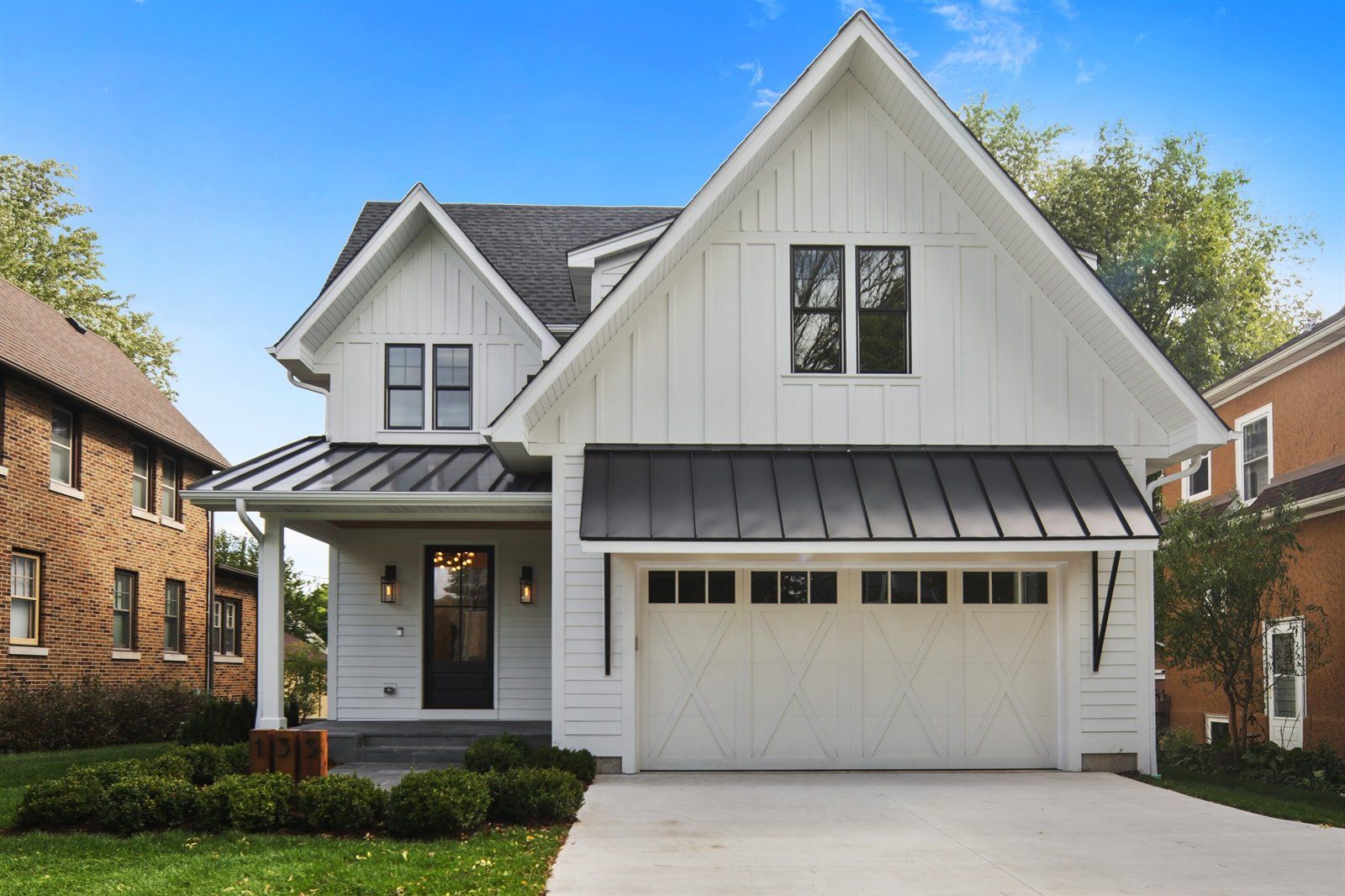 A white house with a black roof and a white garage door.