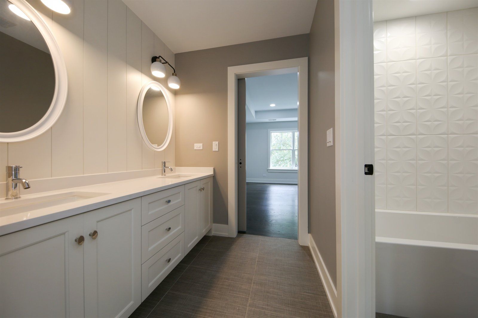 A bathroom with two sinks , two mirrors and a bathtub.
