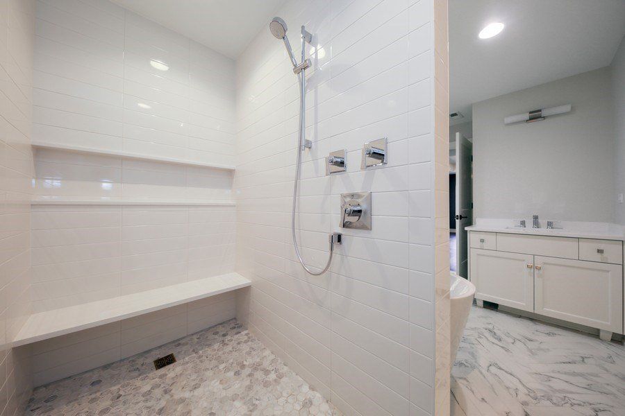 A bathroom with a walk in shower and a bench.