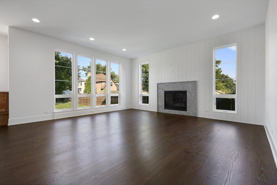 An empty living room with hardwood floors and a fireplace.