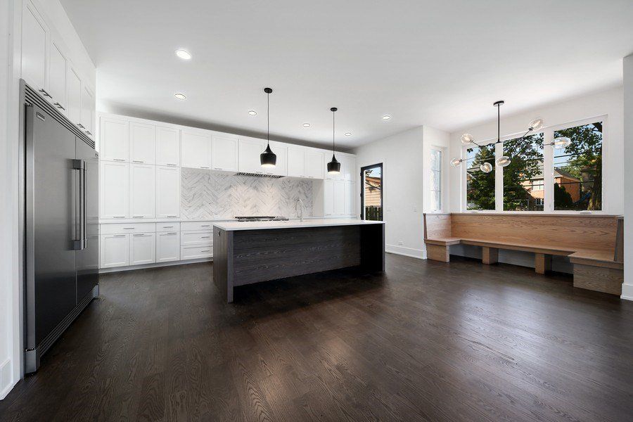 An empty kitchen with a large island and a bench.