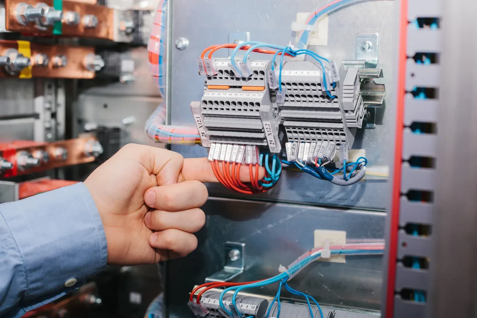 A close up of a person 's hand pointing at an electrical box.