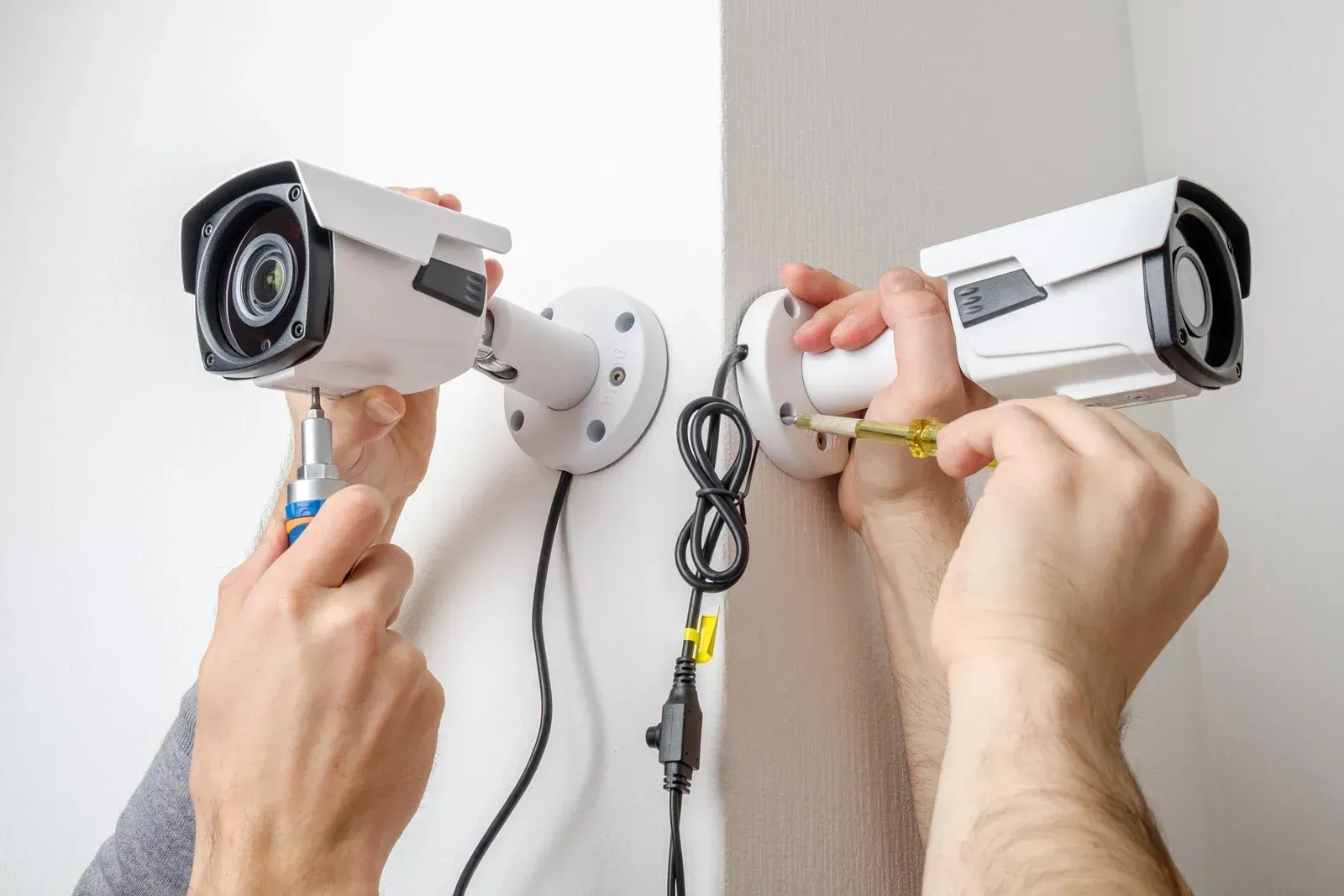 A man is installing a security camera on a wall.