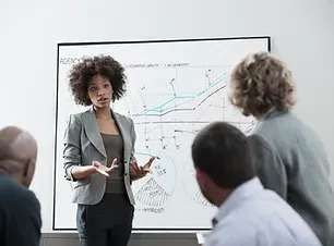 A Woman Is Giving A Presentation To A Group Of People In Front Of A Whiteboard - Phoenix, AZ - Infinite Healing and Wellness