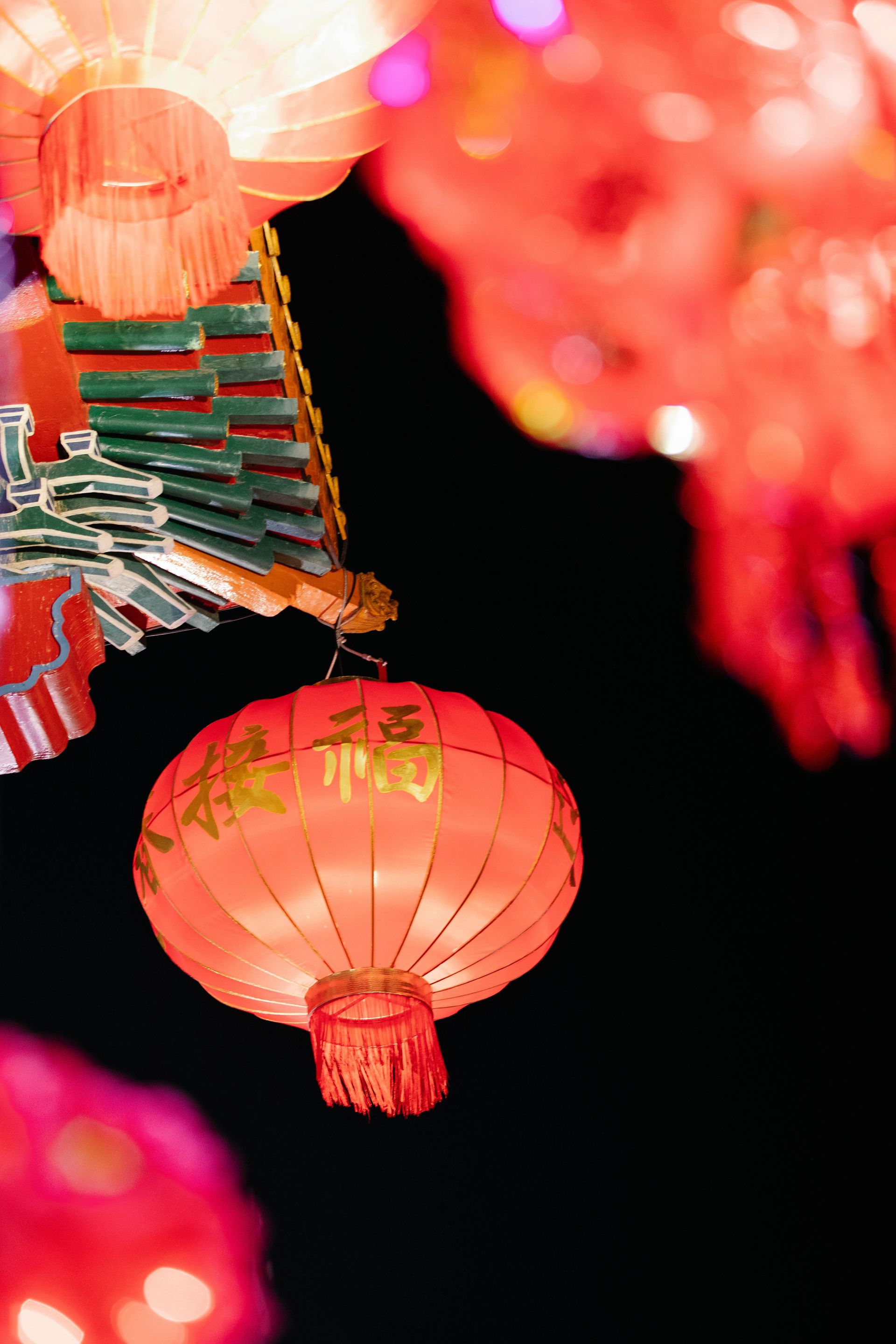 Red Chinese lanterns hanging against a dark background, with gold characters.