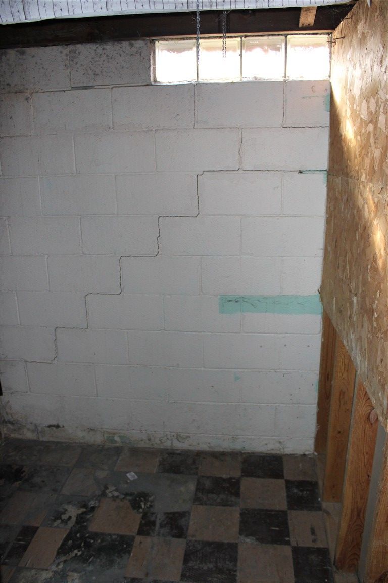 White concrete block basement wall with a stepped crack.