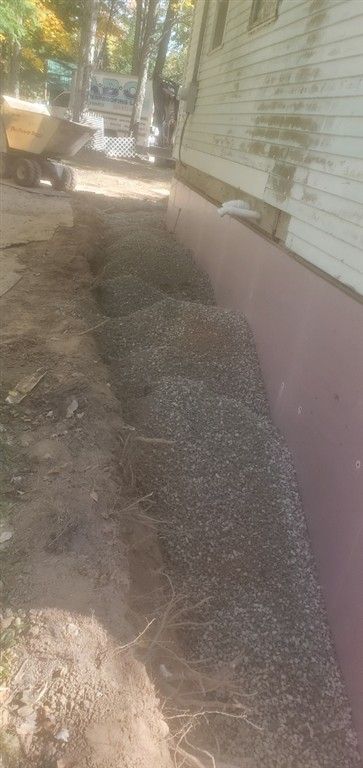 A trench filled with gravel next to a house under construction.