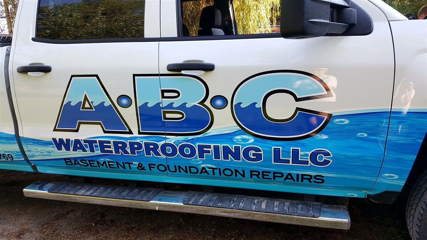 White truck with ABC Waterproofing logo, blue water wave design, step bar.