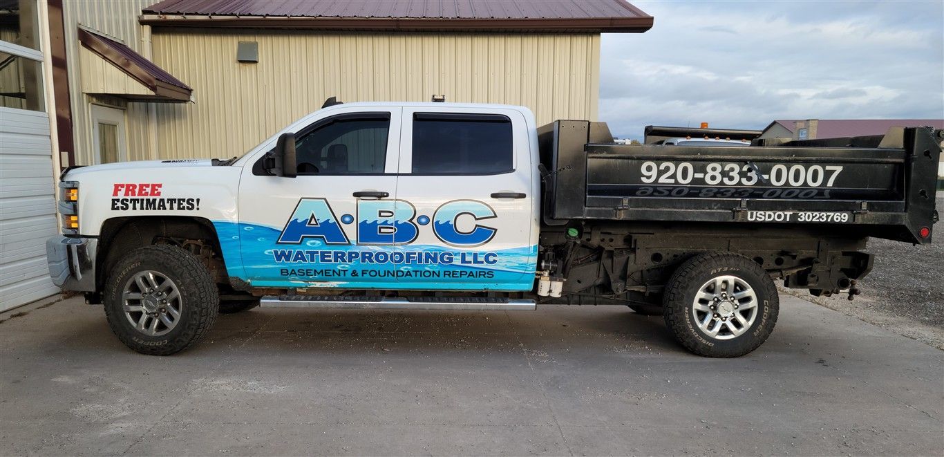 White ABC Water Conditioning LLC dump truck parked by a building. 