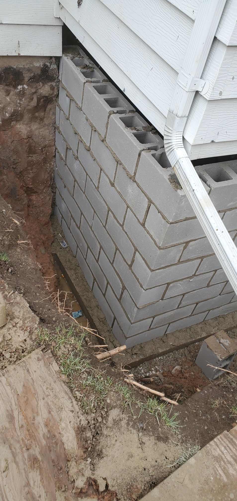Concrete block foundation, dirt and debris around the structure.