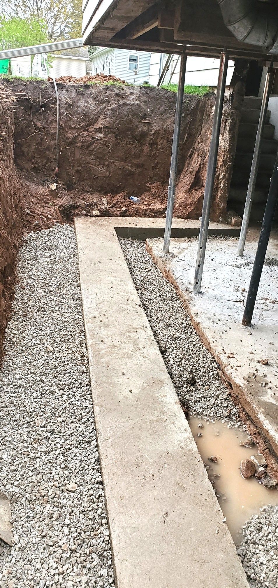 Excavation for a foundation with a concrete footing, gravel base, and soil walls.