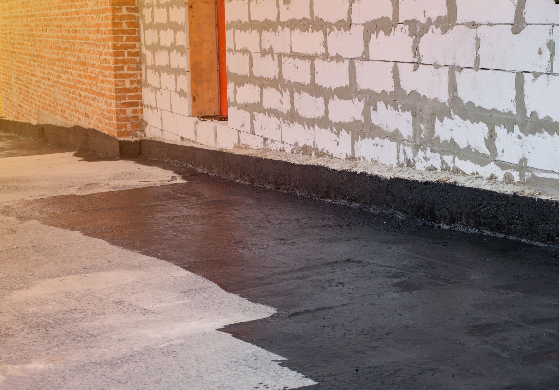 Interior view of a building with a dark, wet coating on the floor and block walls.