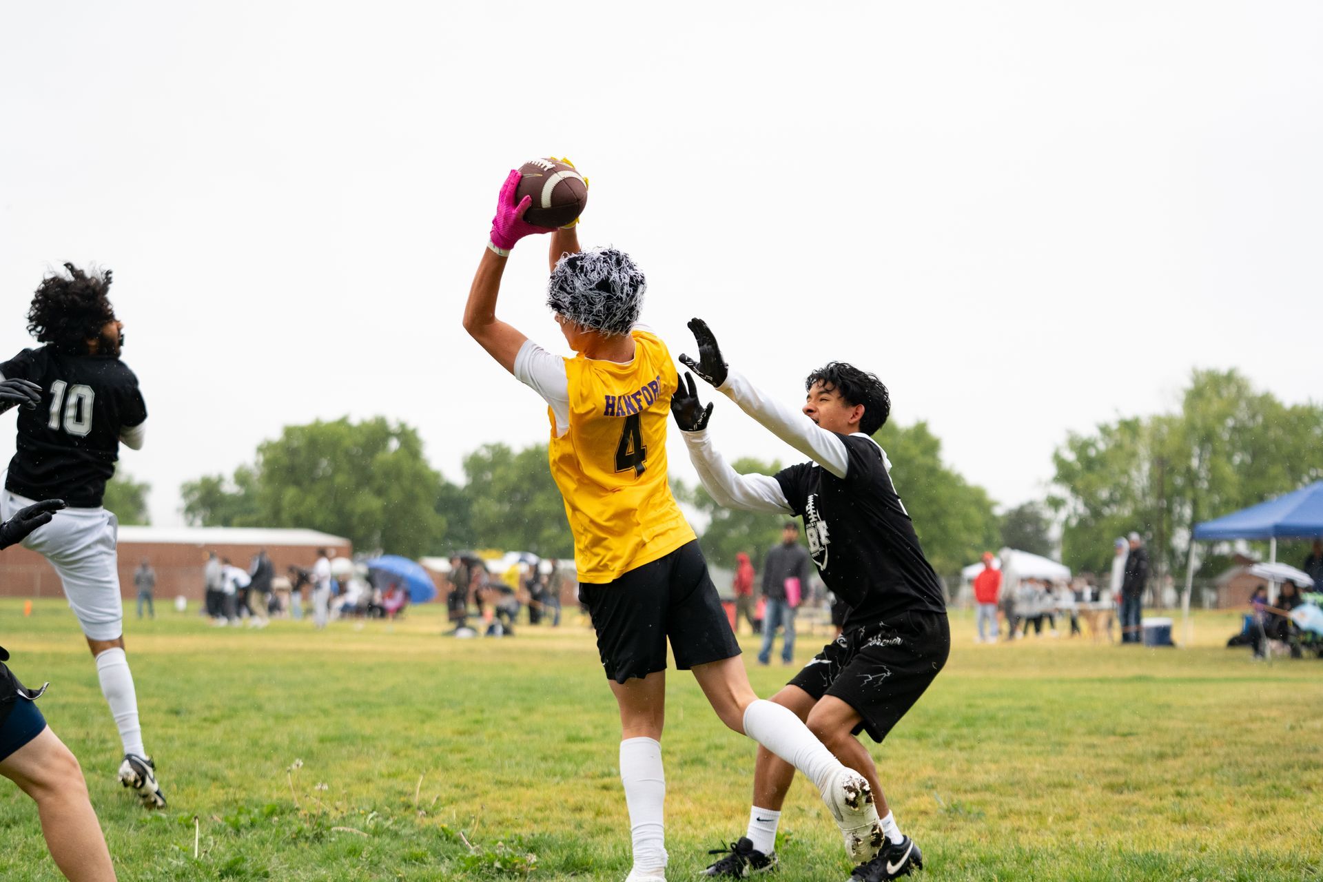 Football player in silver uniform runs with ball on a green field.
