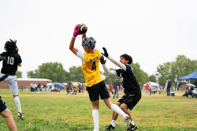 Football player in silver uniform runs with ball on a green field.