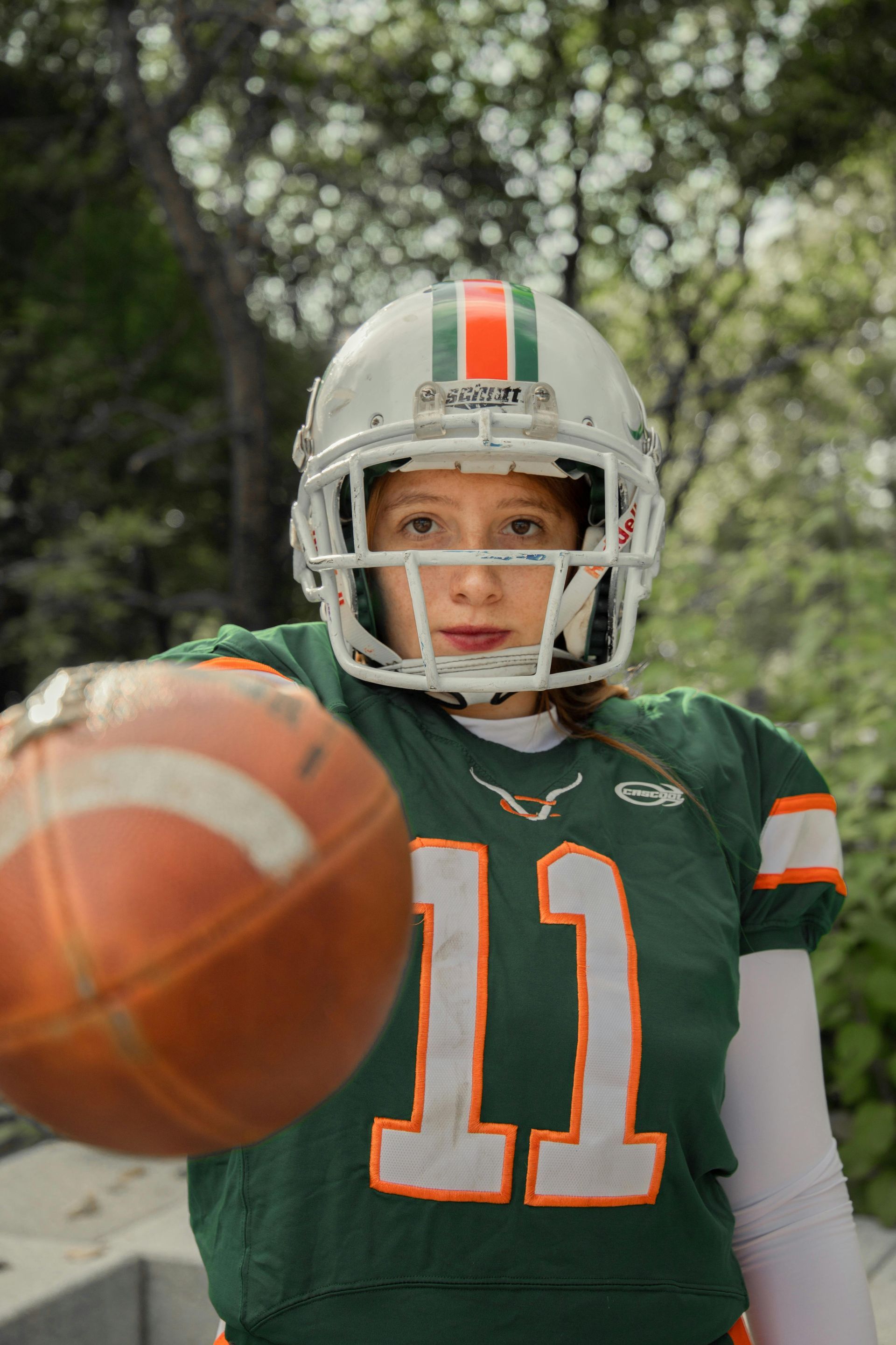 Cheerleader in red uniform performs a backbend on a green and red football field.