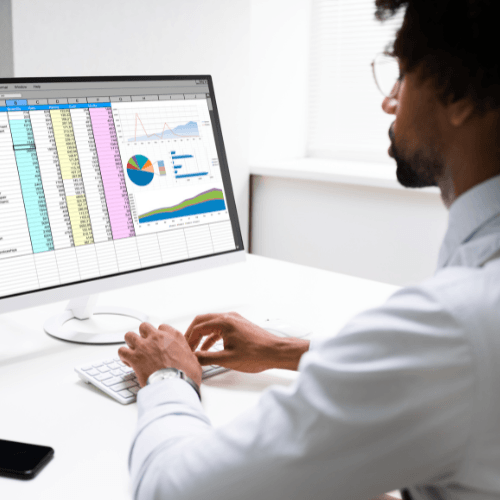 A man is typing on a keyboard in front of a computer monitor.