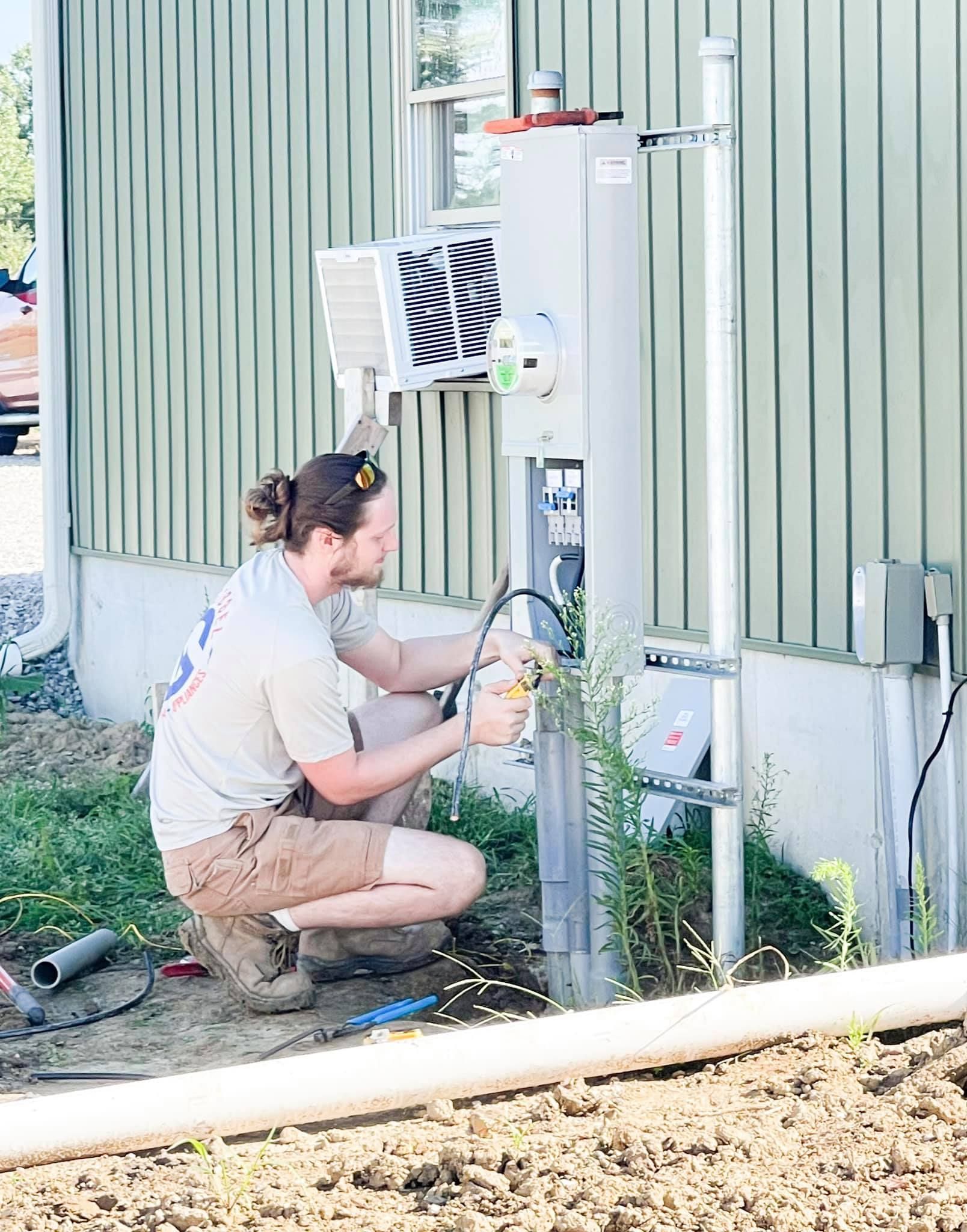 A man is working on an electrical box outside of a house.