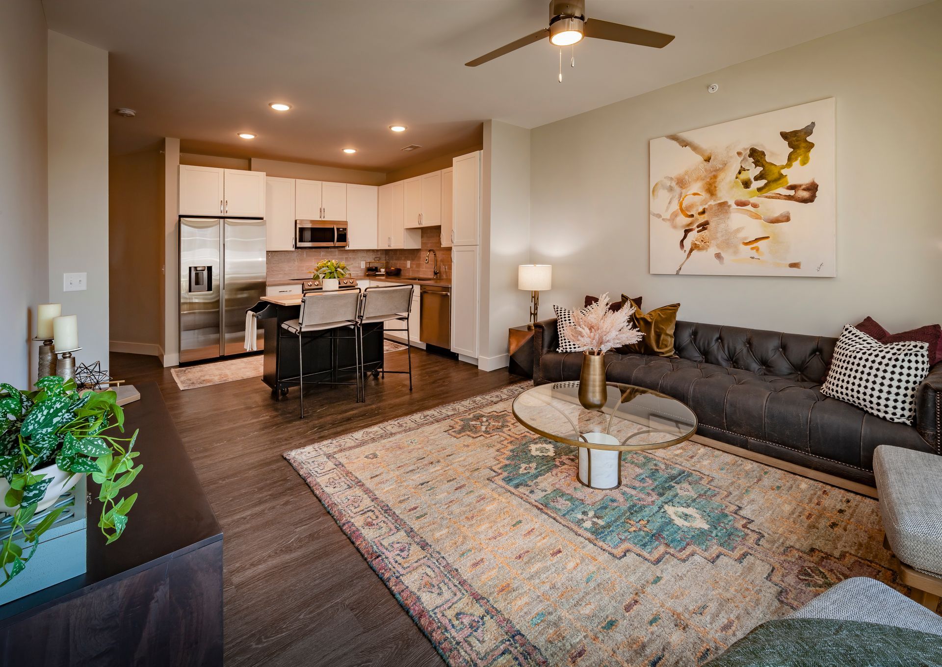 A living room with a couch , rug , coffee table and ceiling fan.