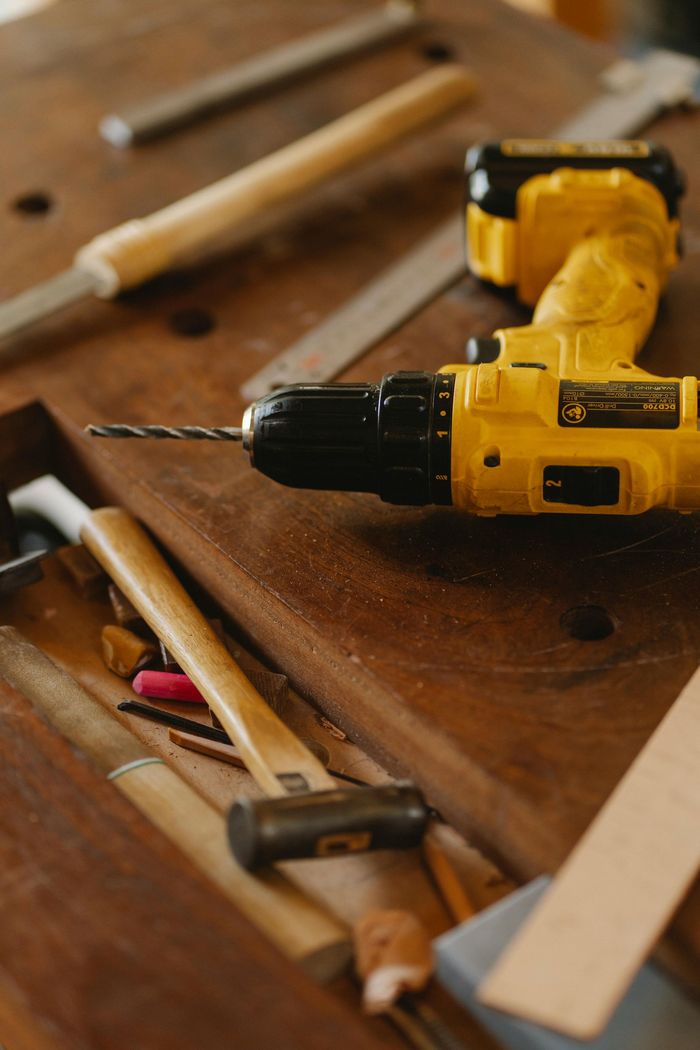 A yellow drill is sitting on top of a wooden table.