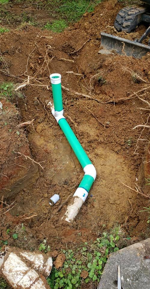 A green pipe is sitting in the middle of a pile of dirt.