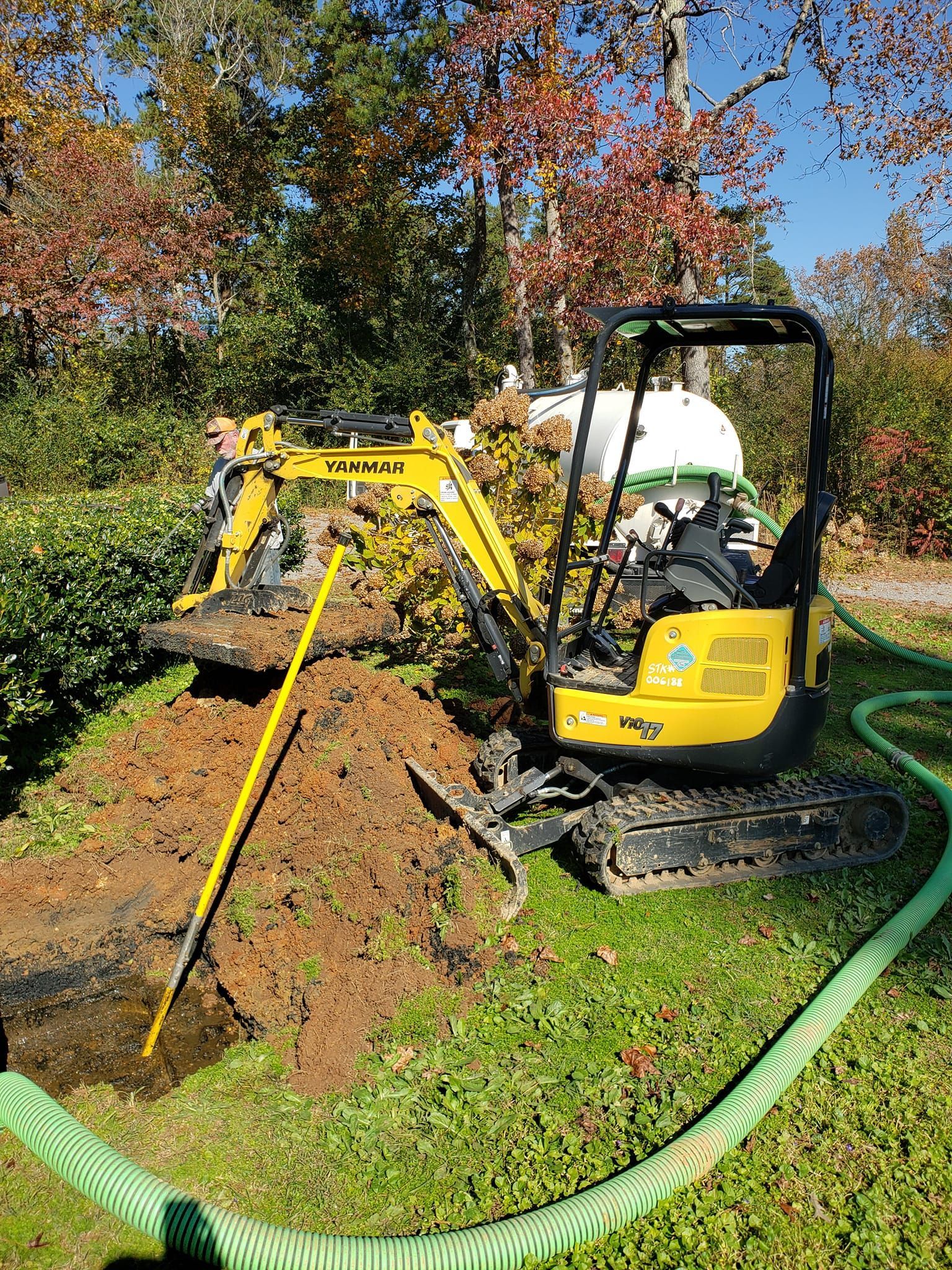 A small yellow excavator is digging a hole in the ground.