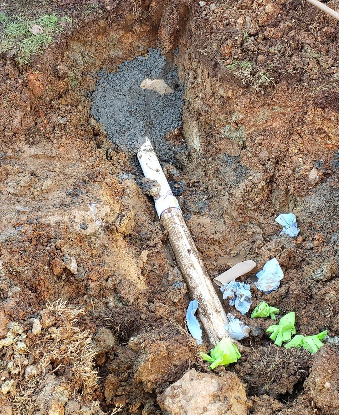 A shovel is laying in the dirt next to a pipe.