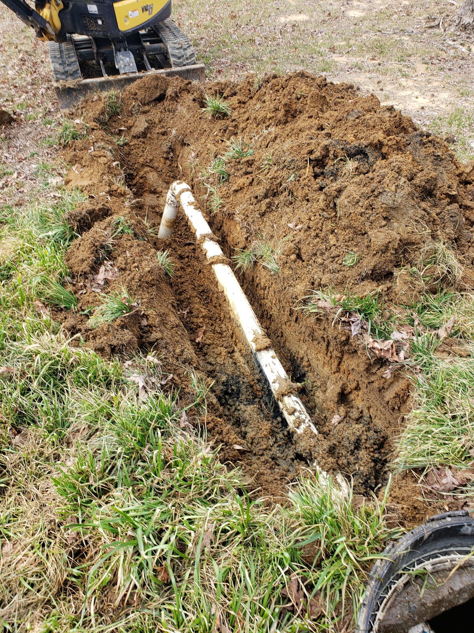 A pipe is being installed in the ground next to a manhole cover.