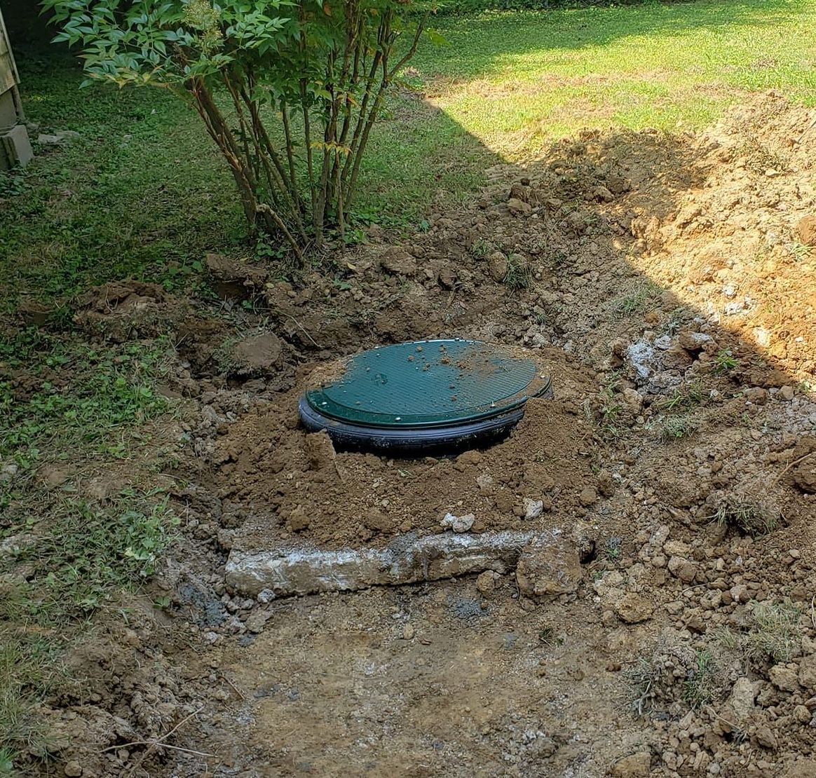 A septic tank is sitting in the middle of a dirt field.