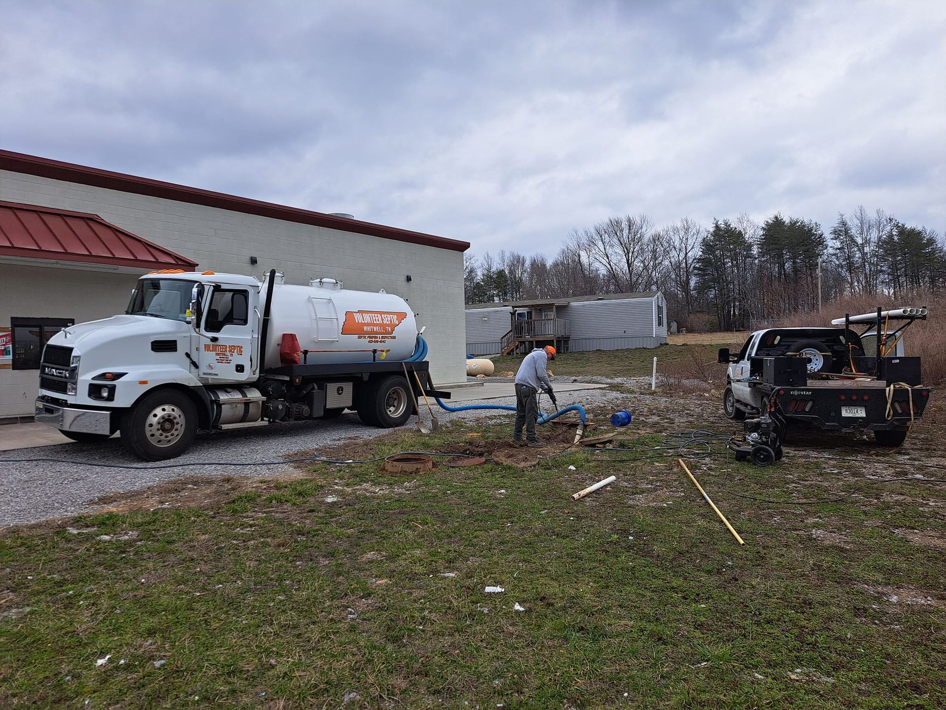 A white truck is parked in a grassy field in front of a building.