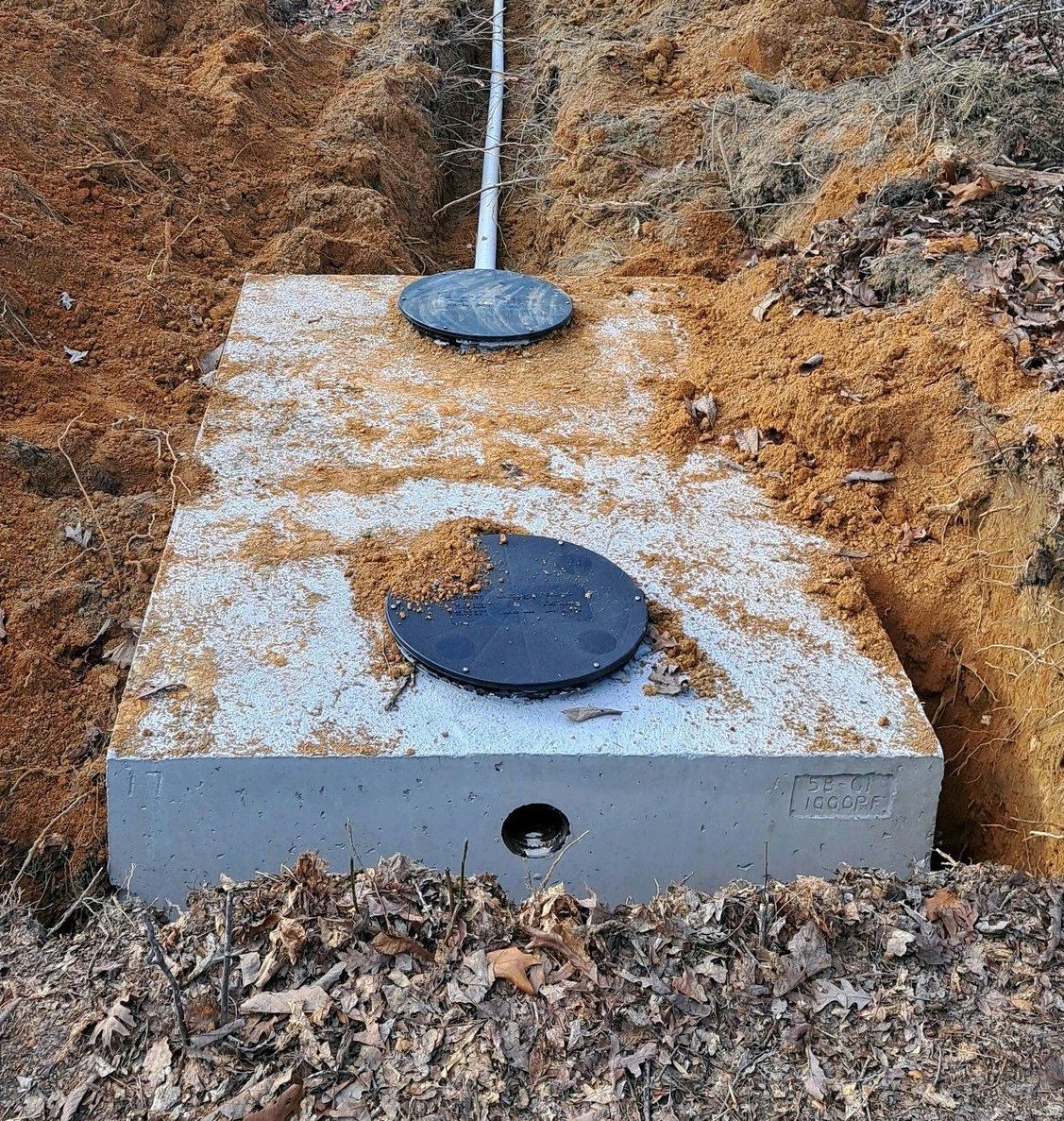 A septic tank is sitting in the middle of a dirt field.