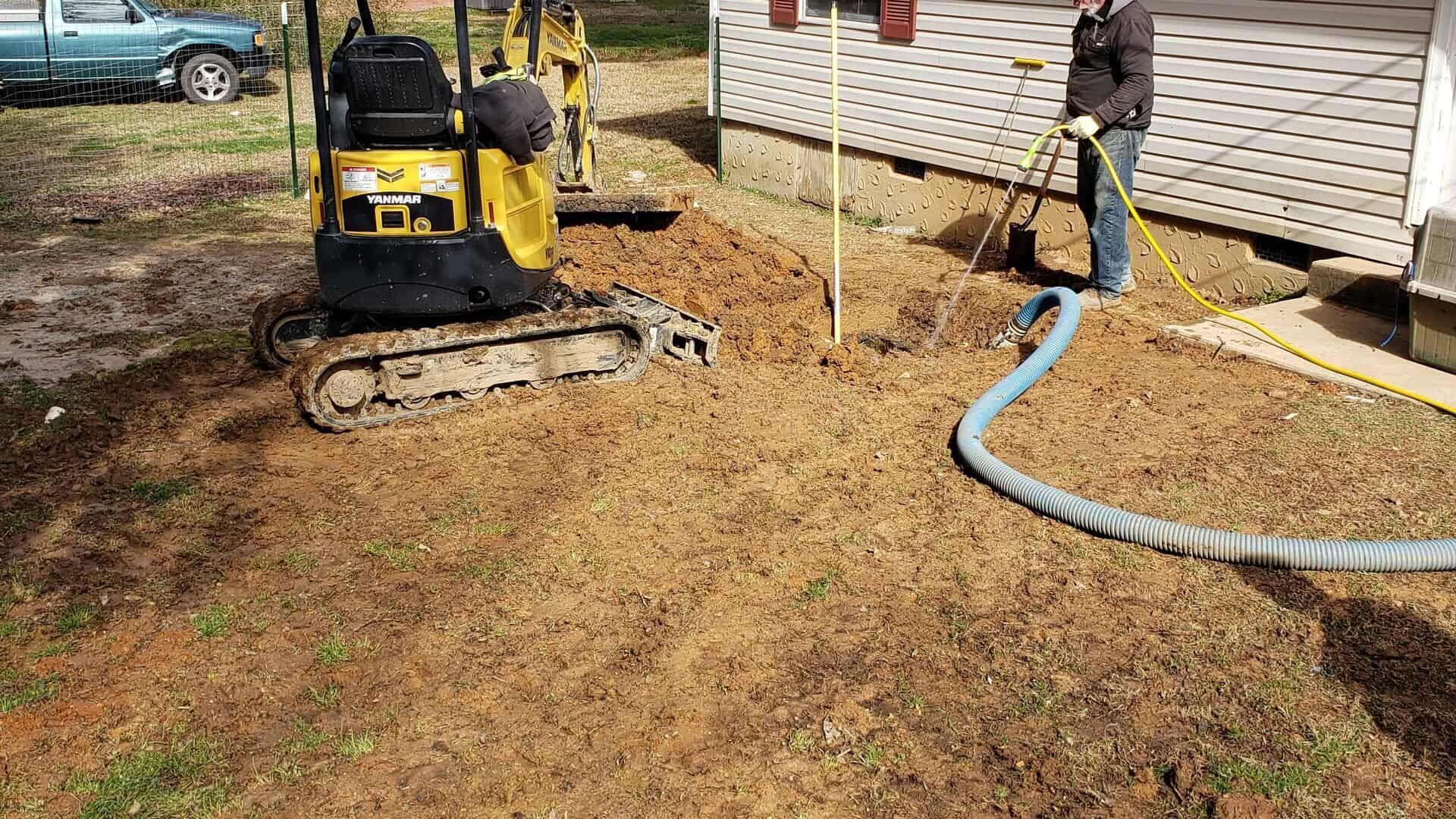 A man is using a hose to pump water into a hole in the ground.