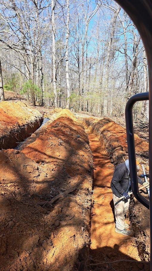 A man is digging a hole in the dirt in the woods.